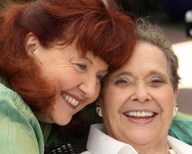 Nancy Clark leaning close to Margaret Anderson as they smile together at Margaret's birthday celebration
